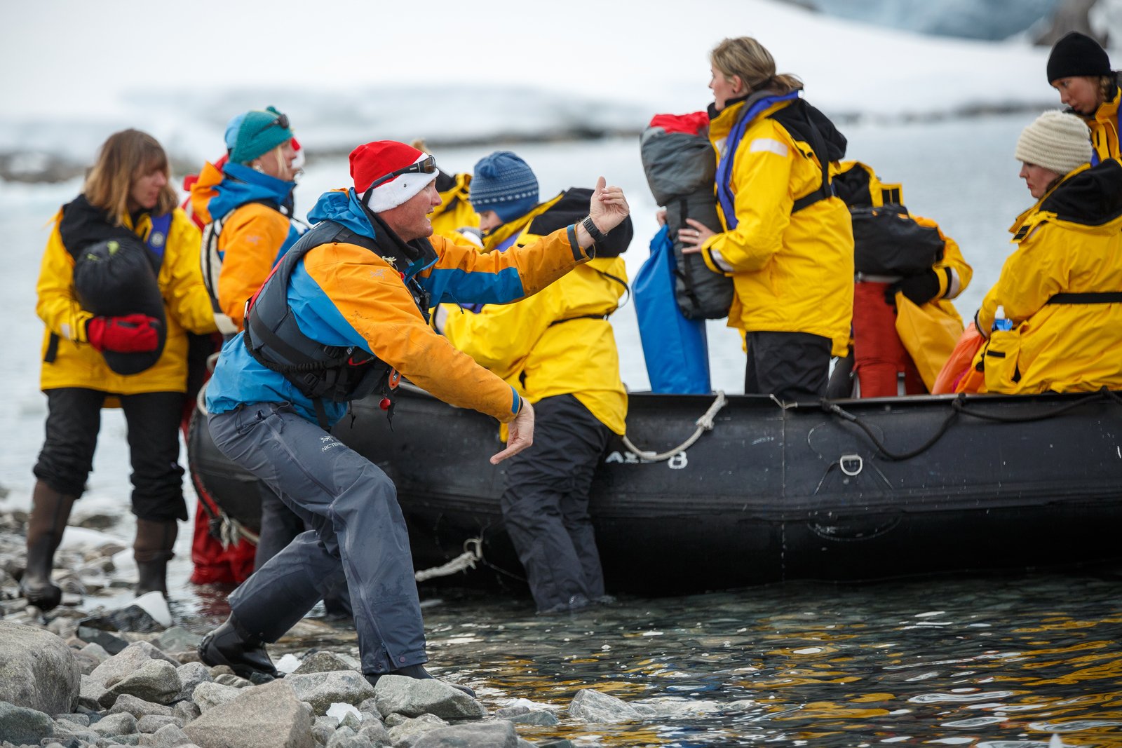 Expedition Team members help passengers disembark zodiacs while on a landing