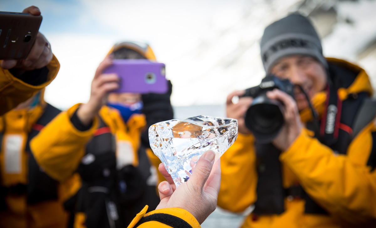 A group of tellow jackets snap a picture of ice held by their guide.